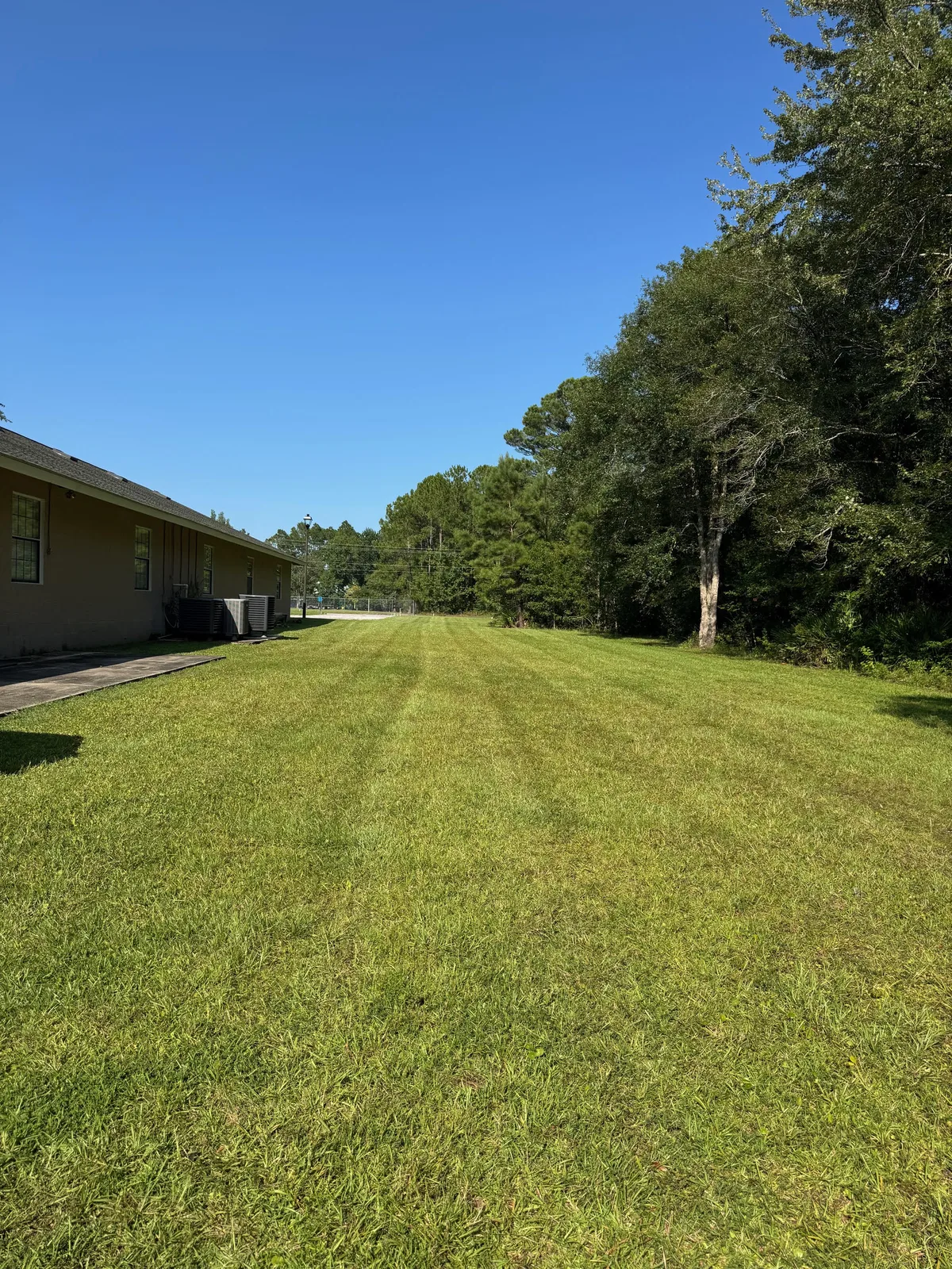 Large maintained lawn beside a building and tree line
