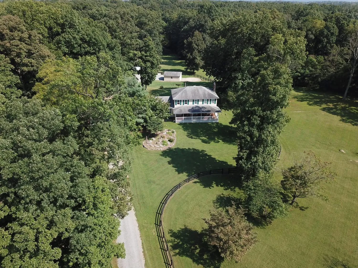 Aerial view of a maintained residential property surrounded by trees and lawn