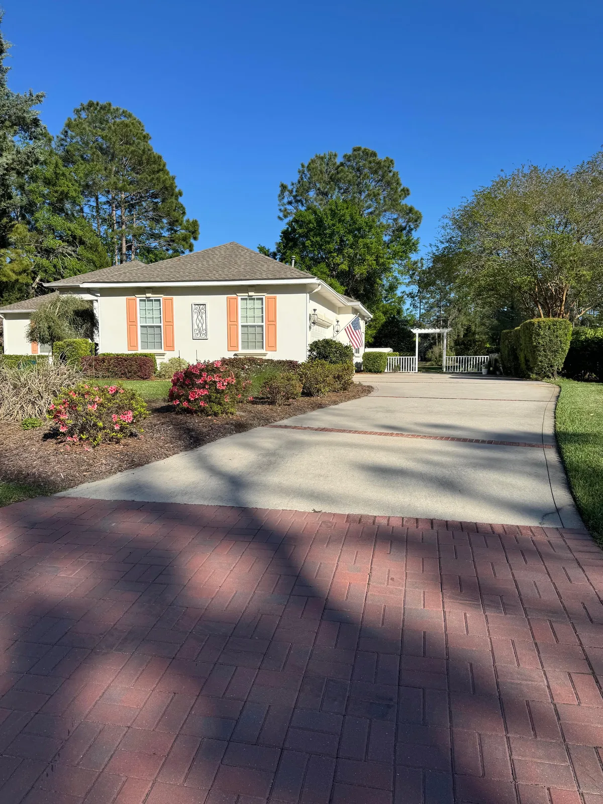 Residential home with maintained lawn, driveway, shrubs, and flower beds