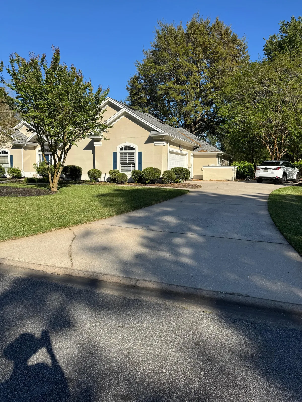 Residential home with maintained front lawn, driveway, and trimmed shrubs